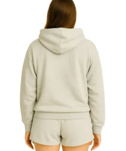 Back view of a woman wearing a plain light grey melange oversized hoodie and matching shorts.