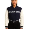 Front of a woman wearing a navy and cream cropped varsity jacket with "GIVENCHY" written in white across the chest.