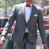 Pee Wee Herman walking outdoors in his classic grey pee wee herman suit with a red bow tie and white shirt.