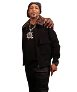 Full-body photo of Katt Williams wearing a black outfit including a Katt Williams Fendi men jacket with a Fendi print collar. This is the Katt Williams Fendi black jacket shown during an interview, showcasing the Katt Williams Fendi designer jacket.