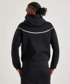 Back view of black reflective Nike Tech fleece tracksuit showing reflective stripe and hood design for men.