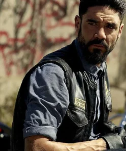 Clayton Cardenas wearing the Mayans M.C Angel Reyes Leather Vest with "Los Asesinos de Dios" patch in a close-up scene.