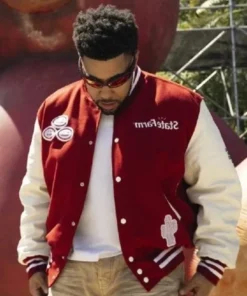 Travis Scott wearing Cactus Jack x State Farm varsity jacket with cactus design and branded front patches.