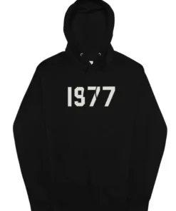 A solid black Fear of God Essentials hoodie with the large numbers "1977" printed in a contrasting light color on the chest.