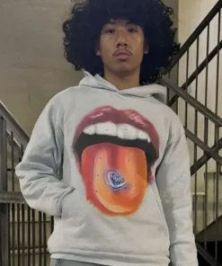 A person wearing a grey homesick hoodie featuring a large graphic of a mouth with red lips and a tongue holding a blue heart.