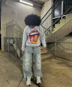 A person posing in a grey homesick hoodie with baggy jeans, highlighting the trendy streetwear aesthetic of the homesick apparel collection.