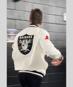 The back of Tom Brady wearing a white Raiders bomber jacket with the large Las Vegas Raiders shield logo and 