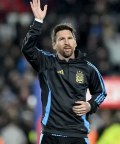 Lionel Messi waving to fans, wearing the official Argentina national team hoodie in black with blue stripes, a potential last home game apparel, showcasing Messi Argentina fan gear.