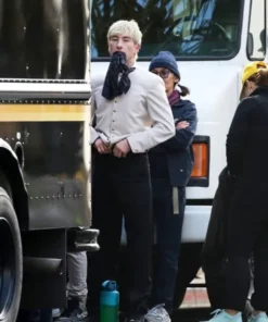 Barry Keoghan dressed in the Crime 101 hotel uniform, a beige bellhop jacket with name tag and dark trousers.