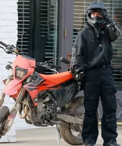 Crime 101 Barry Keoghan black hoodie outfit styled with biker gear and tactical pants on movie set.