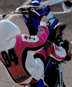 Rider wearing pink and white Supreme Fox Racing Zip Up Hooded Sweatshirt with Pant on motorbike showcasing 94 print and Fox Supreme Factory Team branding.
