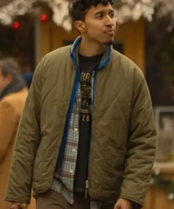 Reda Elazouar with serious expression in The Family Plan 2 Quilted Jacket, seated in a cozy cafe.