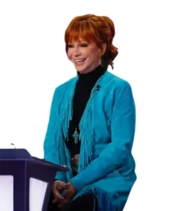 Reba McEntire in the coach chair wearing the The Voice S28 blue fringe coat and a black turtleneck.