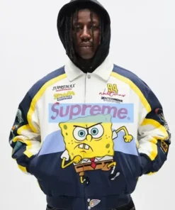 Studio photo of a person wearing the white, navy, and yellow SpongeBob SquarePants jacket or Supreme Racing Jacket, which features Spongebob running on the front.