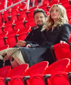 Two film actors stills from Holiday Touchdown: A Bills Love Story featuring actress Alana Higman: one shows her smiling in a dark coat inside a shop with football merchandise, and the other shows her in a dark wool coat seated next to a man in a stadium filled with red seats.