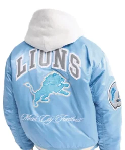 Back of a light blue Detroit Lions satin bomber jacket with "LIONS," a large lion logo, and "Motor City Football."