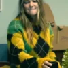 Olivia Holt wearing a yellow fuzzy argyle sweater while seated indoors.