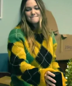 Olivia Holt wearing a yellow fuzzy argyle sweater while seated indoors.