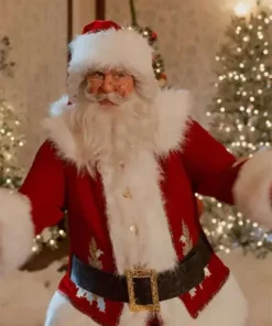 Santa Claus wearing a red coat with white fur trim and a black belt, standing in a cozy room with Christmas trees and warm lights.