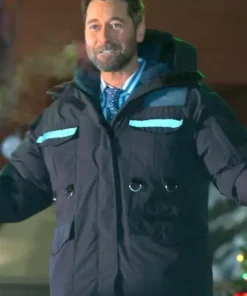 Man wearing a black hooded parka with reflective chest strips in a night outdoor scene.