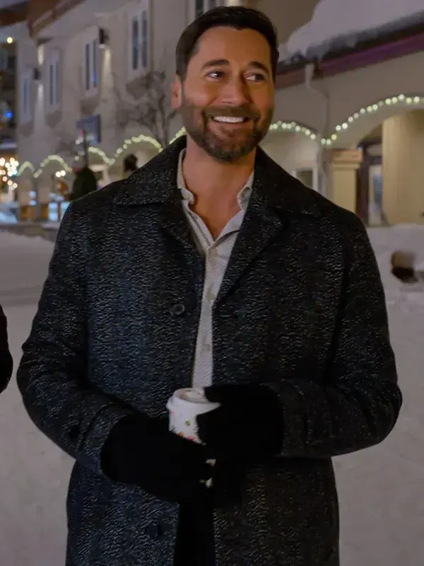 Man wearing a dark black wool coat with a wide collar, standing outdoors in a snowy street at night.
