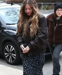 The Housemaid Sydney Sweeney bomber jacket in a dark distressed leather style, paired with a floral dress on the Montclair movie set.