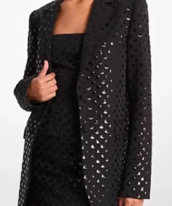 Front view of a black sequin dot blazer with a longline cut and lapel collar, styled over a black outfit.