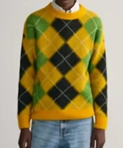 A yellow fuzzy sweater with green and black argyle pattern worn with jeans.