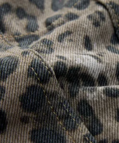 Close-up of high-quality denim leopard print jacket fabric, showing the detailed animal pattern and the durable twill weave texture.