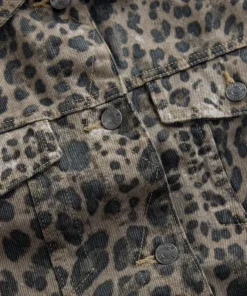 Detailed shot of a denim jacket with leopard print, highlighting the metal buttons, flap chest pockets, and precision contrast stitching.