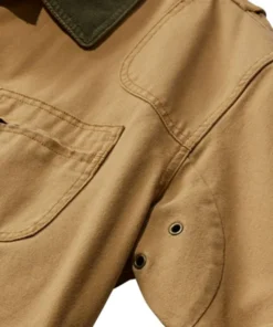 Close-up of a Men's Cotton Brown Jacket showing the durable fabric texture, reinforced shoulder stitching, and metal underarm ventilation eyelets.