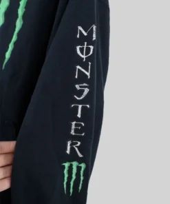 Detailed view of the white text branding on the sleeve of a monster energy drink jacket with a small green claw logo.