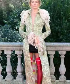 Margot Robbie in an archival John Galliano coat featuring a long silhouette, feathered collar, and vibrant red stockings.