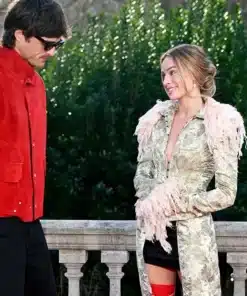 Margot Robbie smiles at Jacob Elordi while wearing a Galliano feather trim long coat, a highlight of her Wuthering Heights press tour.